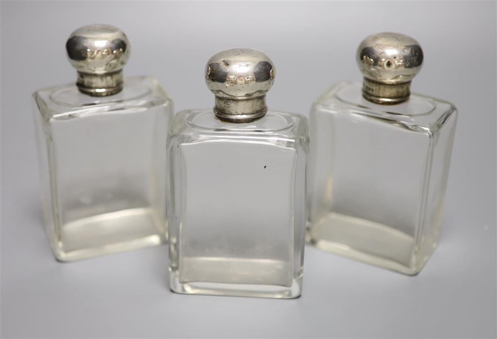 A set of three George V silver topped glass toilet jars, London, 1912, 13.2cm, with engraved initial.